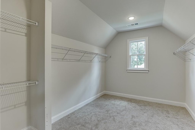 spacious closet featuring lofted ceiling, visible vents, and light colored carpet