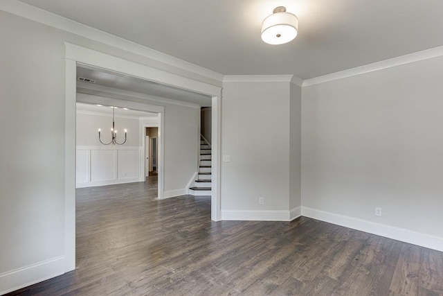 spare room with dark wood-style flooring, visible vents, baseboards, ornamental molding, and stairway