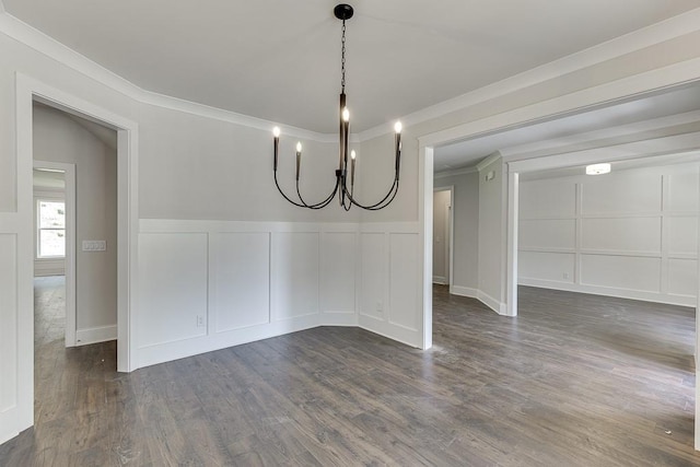 unfurnished dining area with crown molding, dark wood-style flooring, a wainscoted wall, and a decorative wall