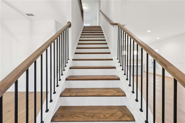 stairway featuring wood finished floors, visible vents, and recessed lighting