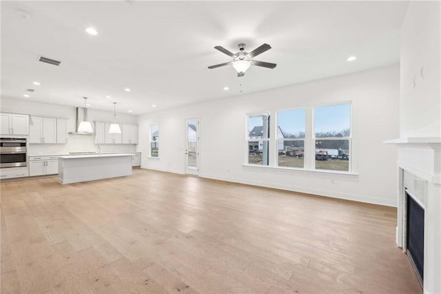 unfurnished living room featuring recessed lighting, visible vents, a fireplace, and light wood finished floors