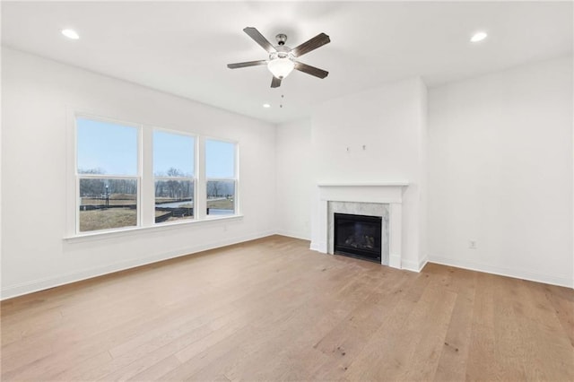 unfurnished living room featuring light wood finished floors, a premium fireplace, recessed lighting, and baseboards