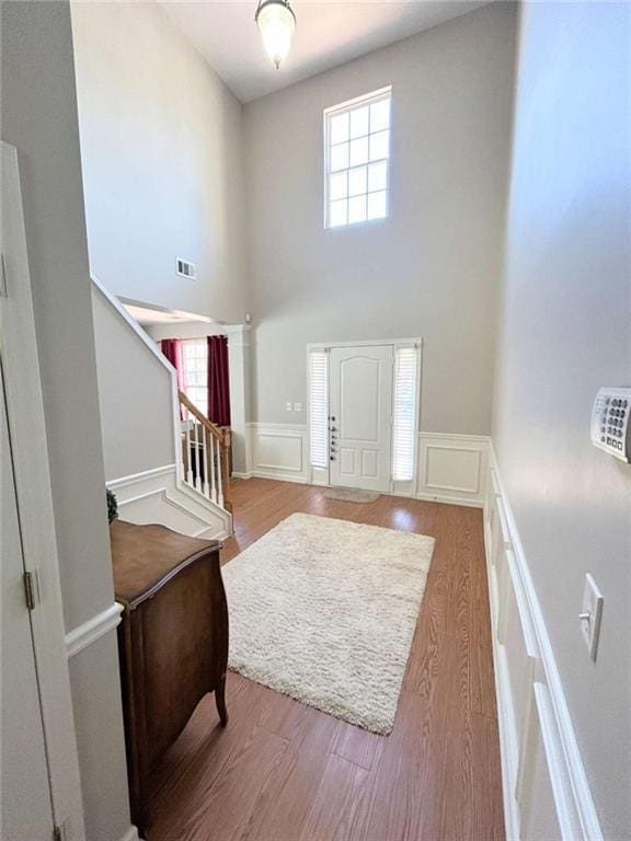 foyer with a wealth of natural light, a decorative wall, wainscoting, and wood finished floors