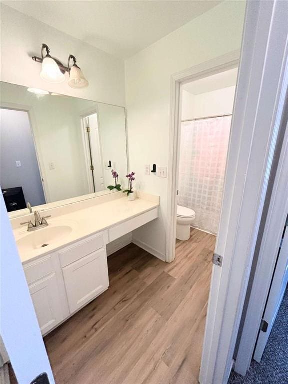 full bath with toilet, wood finished floors, and vanity