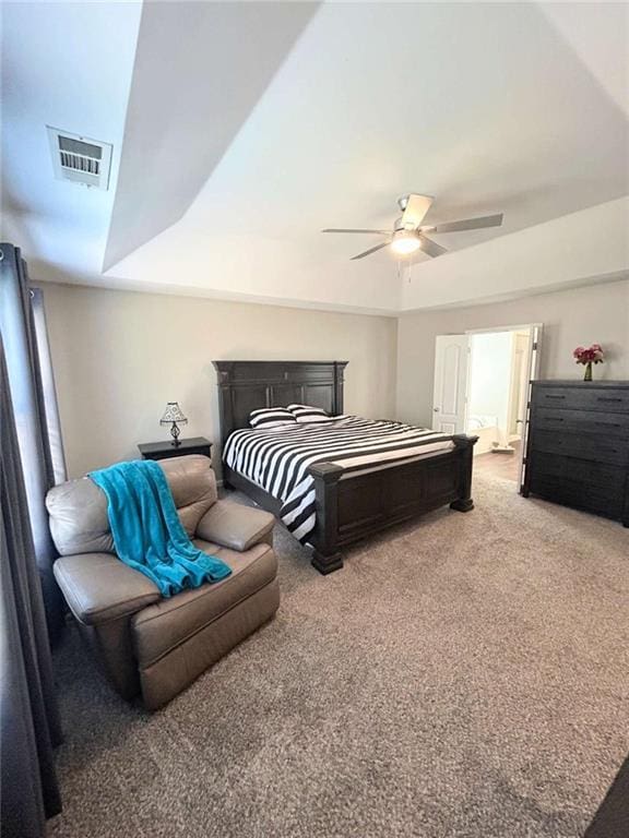 bedroom featuring a raised ceiling, visible vents, carpet floors, and ceiling fan