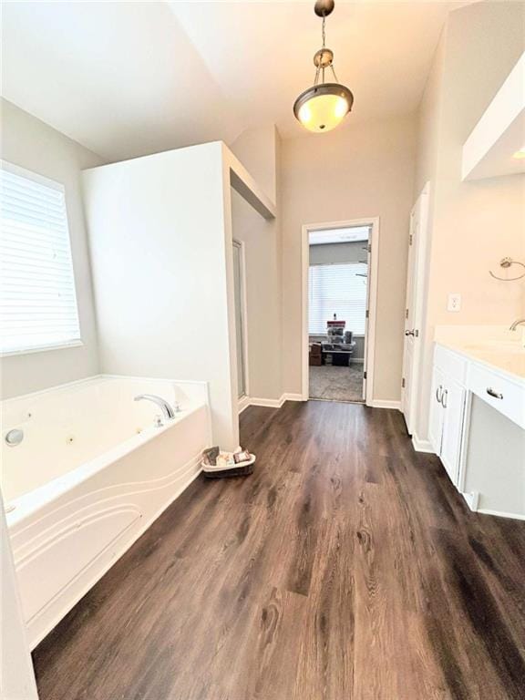 full bathroom featuring plenty of natural light, vanity, a garden tub, and wood finished floors