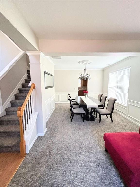 interior space featuring a notable chandelier, a decorative wall, stairway, and carpet