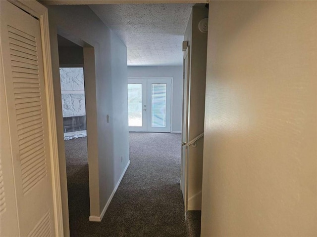 hall featuring a textured ceiling, dark carpet, and french doors