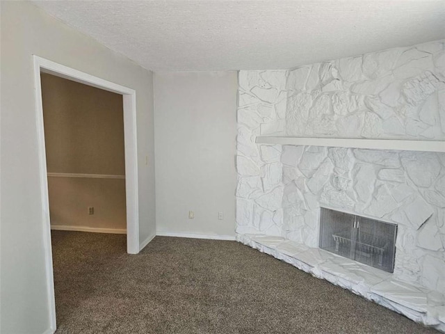 unfurnished living room featuring a stone fireplace, carpet floors, and a textured ceiling