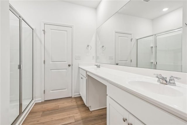 bathroom featuring wood-type flooring, vanity, and a shower with shower door