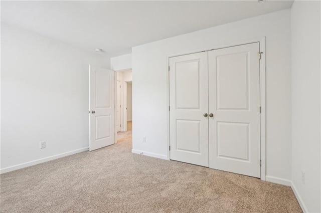 unfurnished bedroom featuring light colored carpet and a closet