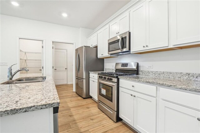 kitchen featuring white cabinets, appliances with stainless steel finishes, light hardwood / wood-style floors, and sink