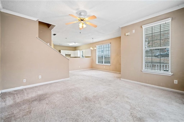 unfurnished living room with light colored carpet, ornamental molding, ceiling fan with notable chandelier, and a textured ceiling