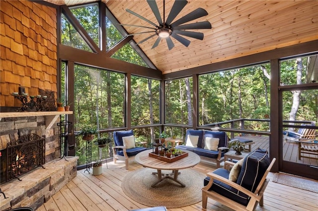 sunroom / solarium featuring lofted ceiling, plenty of natural light, a fireplace, and ceiling fan