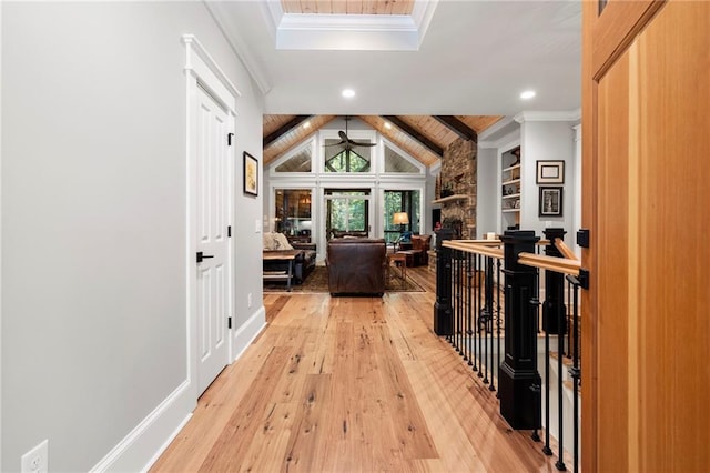 corridor with ornamental molding, lofted ceiling with skylight, built in features, and light hardwood / wood-style flooring