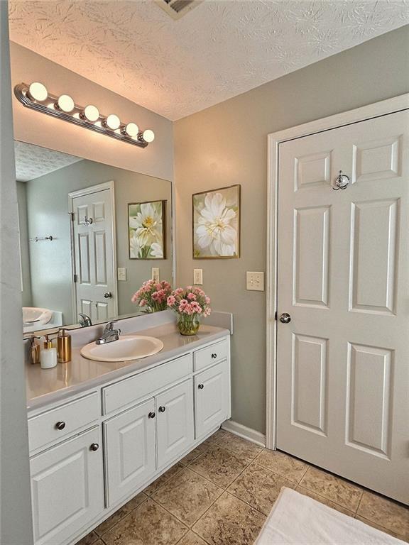 bathroom with tile patterned floors, vanity, and a textured ceiling