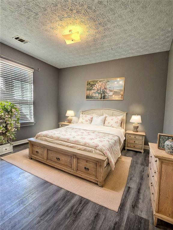 bedroom featuring dark hardwood / wood-style flooring and a textured ceiling