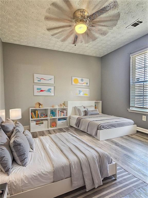 bedroom featuring ceiling fan, hardwood / wood-style flooring, and a textured ceiling