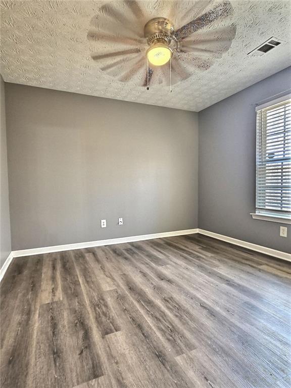 empty room featuring hardwood / wood-style flooring, ceiling fan, and a textured ceiling