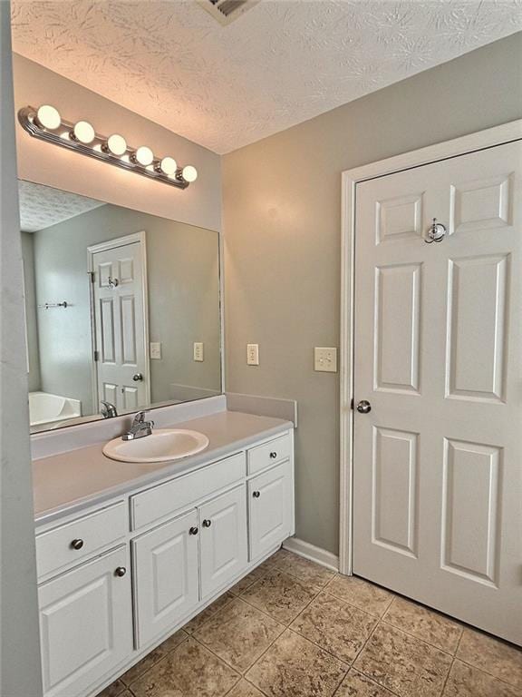 bathroom with tile patterned flooring, vanity, and a textured ceiling