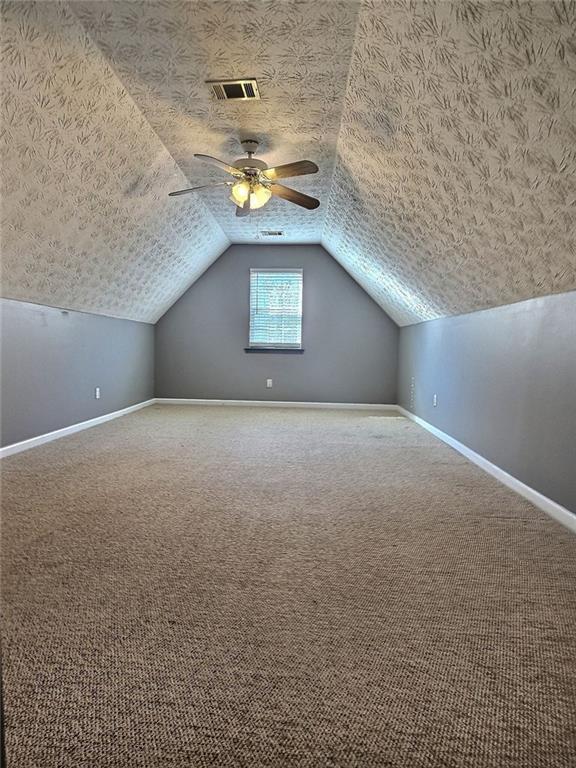 bonus room with lofted ceiling, ceiling fan, a textured ceiling, and carpet flooring