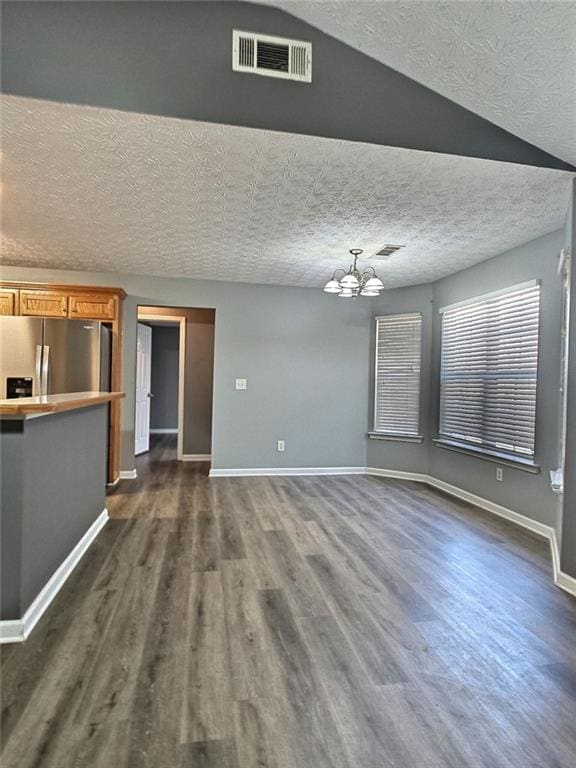 unfurnished living room featuring a textured ceiling, a notable chandelier, and dark hardwood / wood-style flooring