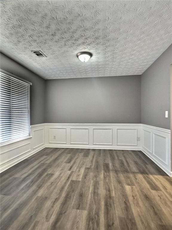 empty room featuring dark hardwood / wood-style flooring and a textured ceiling