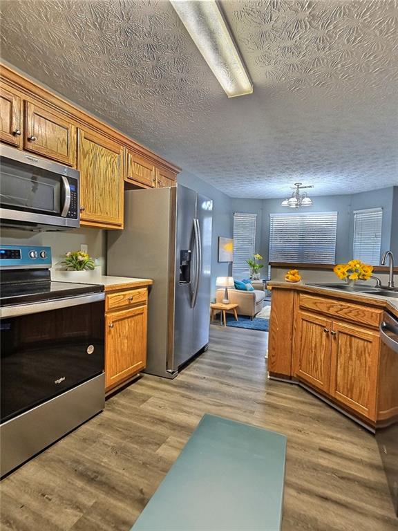 kitchen featuring hardwood / wood-style floors, a notable chandelier, sink, and appliances with stainless steel finishes