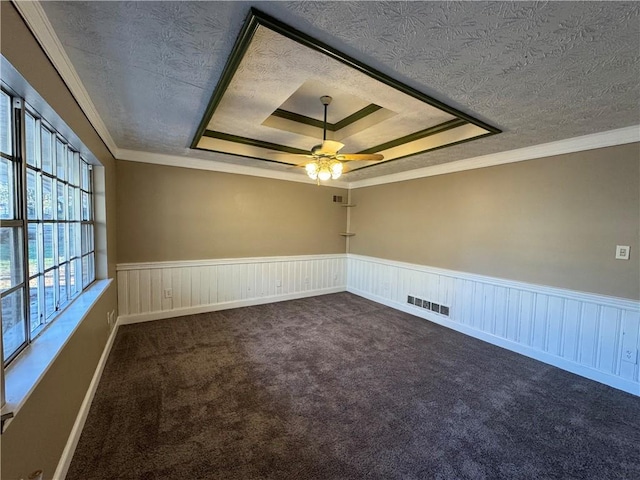 carpeted empty room featuring a textured ceiling, a tray ceiling, ceiling fan, and ornamental molding