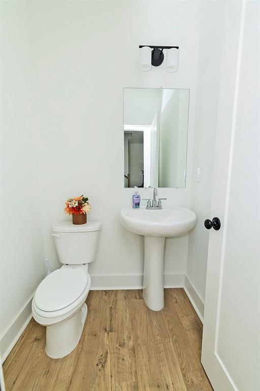 1433 Halpern Ln, Kennesaw, GA 30144 - half bathroom featuring toilet, a sink, baseboards, and wood finished floors