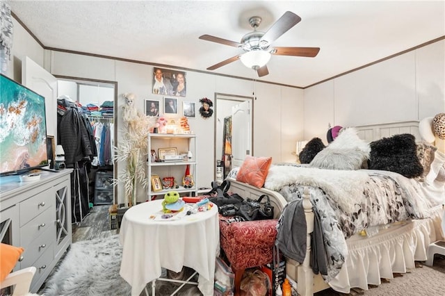 bedroom with crown molding, a spacious closet, ceiling fan, and a closet