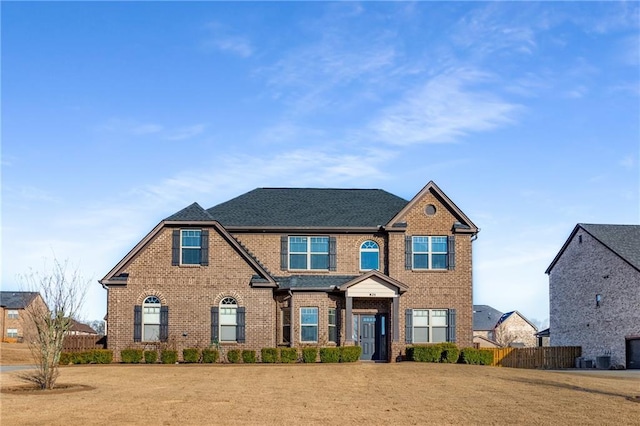 view of front of home featuring brick siding, a front yard, and fence