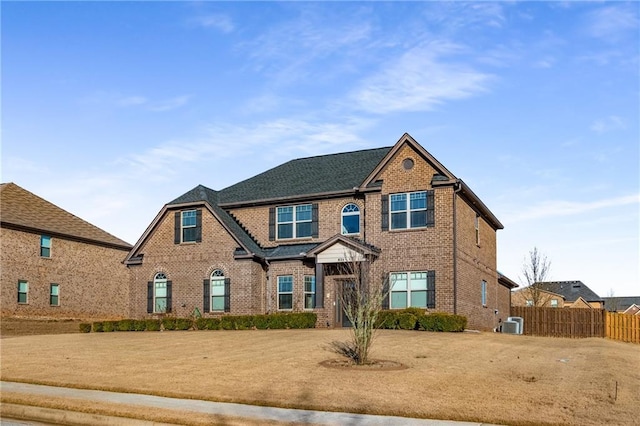 view of front of property with cooling unit, brick siding, and fence