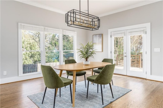 dining area featuring a notable chandelier, wood finished floors, french doors, and crown molding