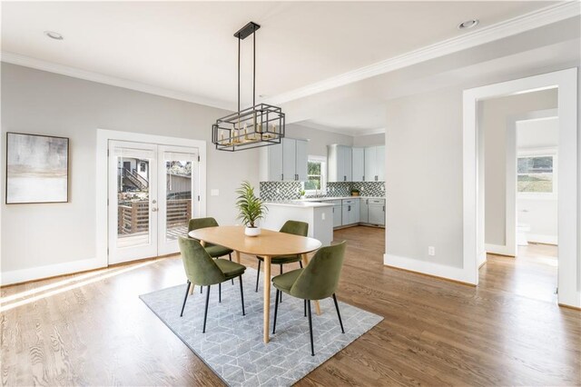 dining area featuring baseboards, ornamental molding, wood finished floors, and a chandelier