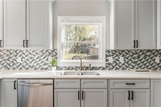 kitchen with stainless steel dishwasher, gray cabinets, light countertops, and a sink
