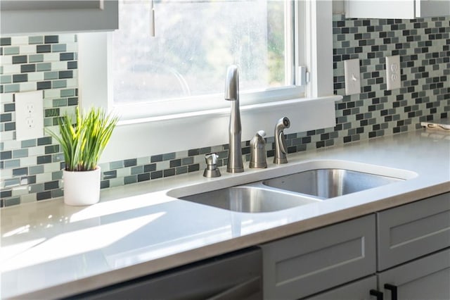 room details featuring backsplash, gray cabinets, a sink, and light countertops