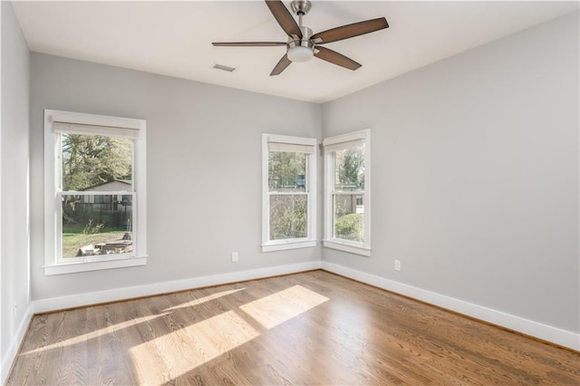 spare room featuring plenty of natural light, visible vents, and wood finished floors