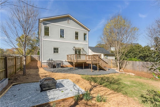 back of house featuring stairs, a fenced backyard, a deck, a fire pit, and a yard