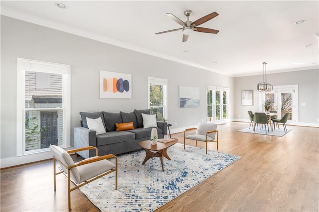 living area with baseboards, crown molding, wood finished floors, and a ceiling fan