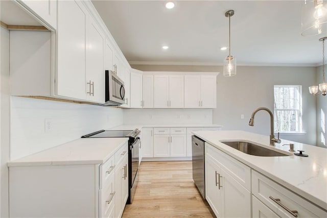 93 Portico Pl, Newnan, GA 30265 - kitchen featuring appliances with stainless steel finishes, white cabinets, pendant lighting, light wood finished floors, and ornamental molding