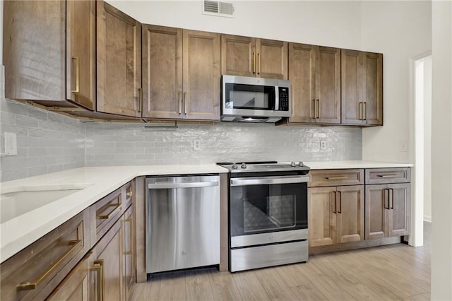 215 Maplewood Dr SW, Calhoun, GA 30701 - kitchen featuring appliances with stainless steel finishes, light countertops, light wood-type flooring, and backsplash