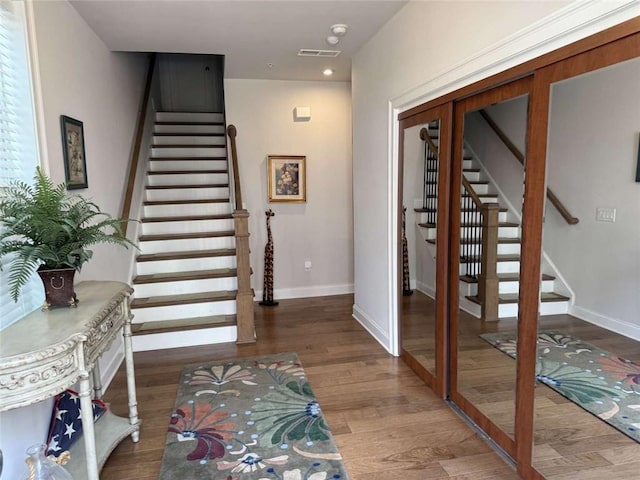 entryway featuring stairway, visible vents, baseboards, and wood finished floors