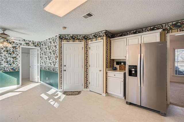 kitchen with white cabinetry, ceiling fan, stainless steel fridge, and a textured ceiling