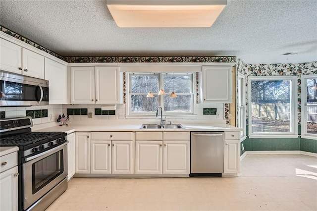 kitchen featuring appliances with stainless steel finishes, sink, a textured ceiling, and white cabinets