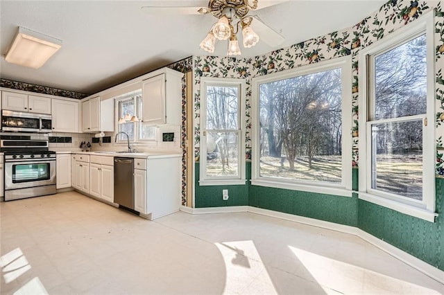 kitchen featuring appliances with stainless steel finishes, sink, white cabinets, and ceiling fan