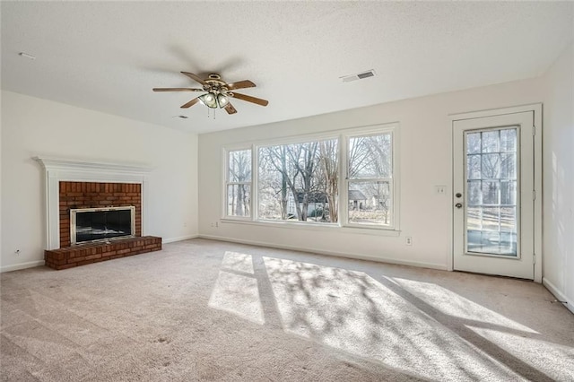 unfurnished living room featuring a brick fireplace, light carpet, and ceiling fan