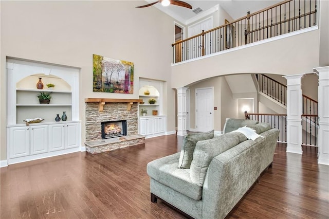 living room featuring decorative columns, built in features, and wood finished floors