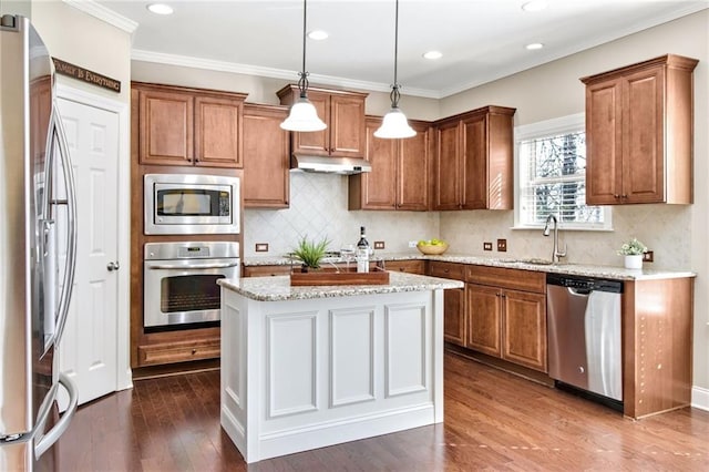 kitchen featuring appliances with stainless steel finishes, brown cabinetry, a sink, and under cabinet range hood