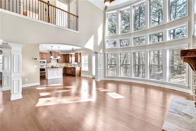 living room with arched walkways, baseboards, decorative columns, and hardwood / wood-style floors